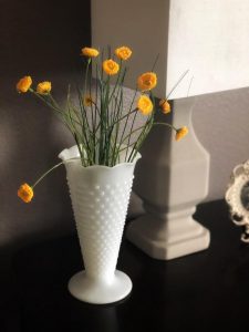 Vintage Hobnail Milk Glass Vase filled with flowers placed next to a lamp on a side table.