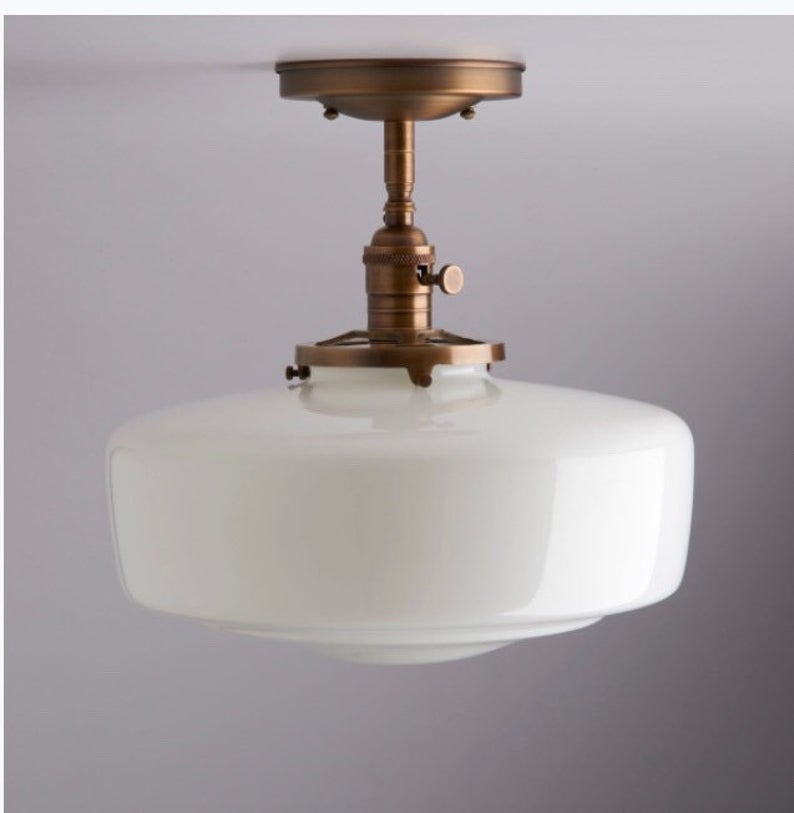 Flush mount milk glass light fixture with antique brass hardware. 