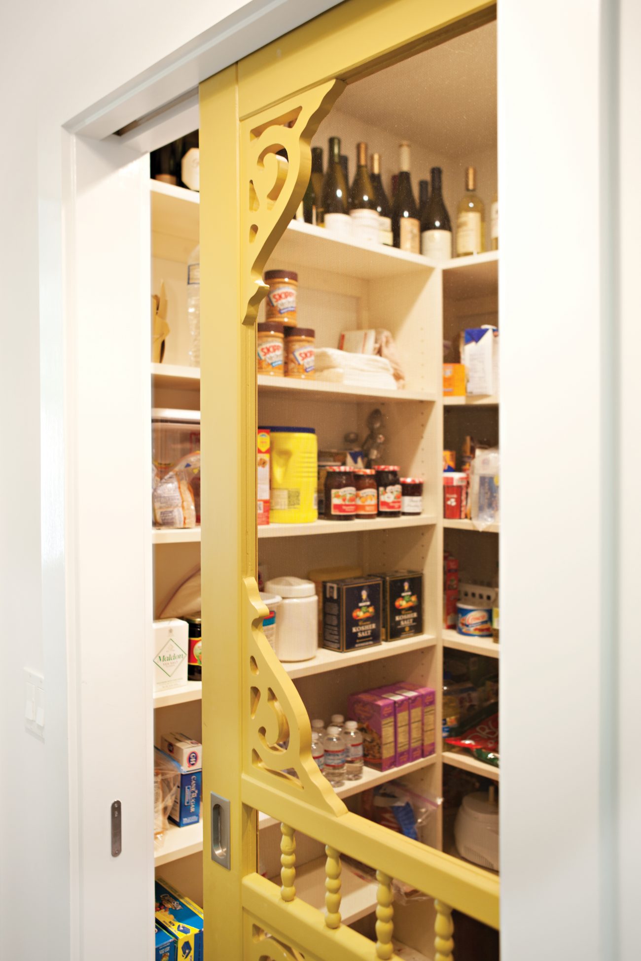 A screen door with vintage-inspired wood work serving as a pocket pantry door.