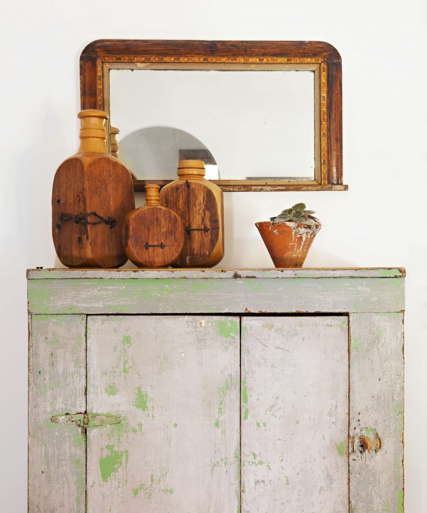 Vintage cabinet with antique pottery and mirror above it