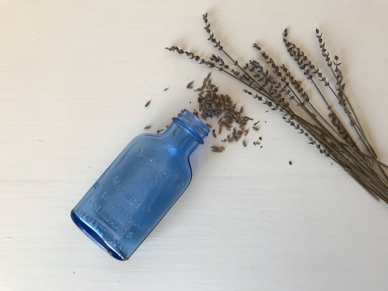 Hazel Atlas Blue Glass Medicine Bottle laid next to dried lavender stalks. 