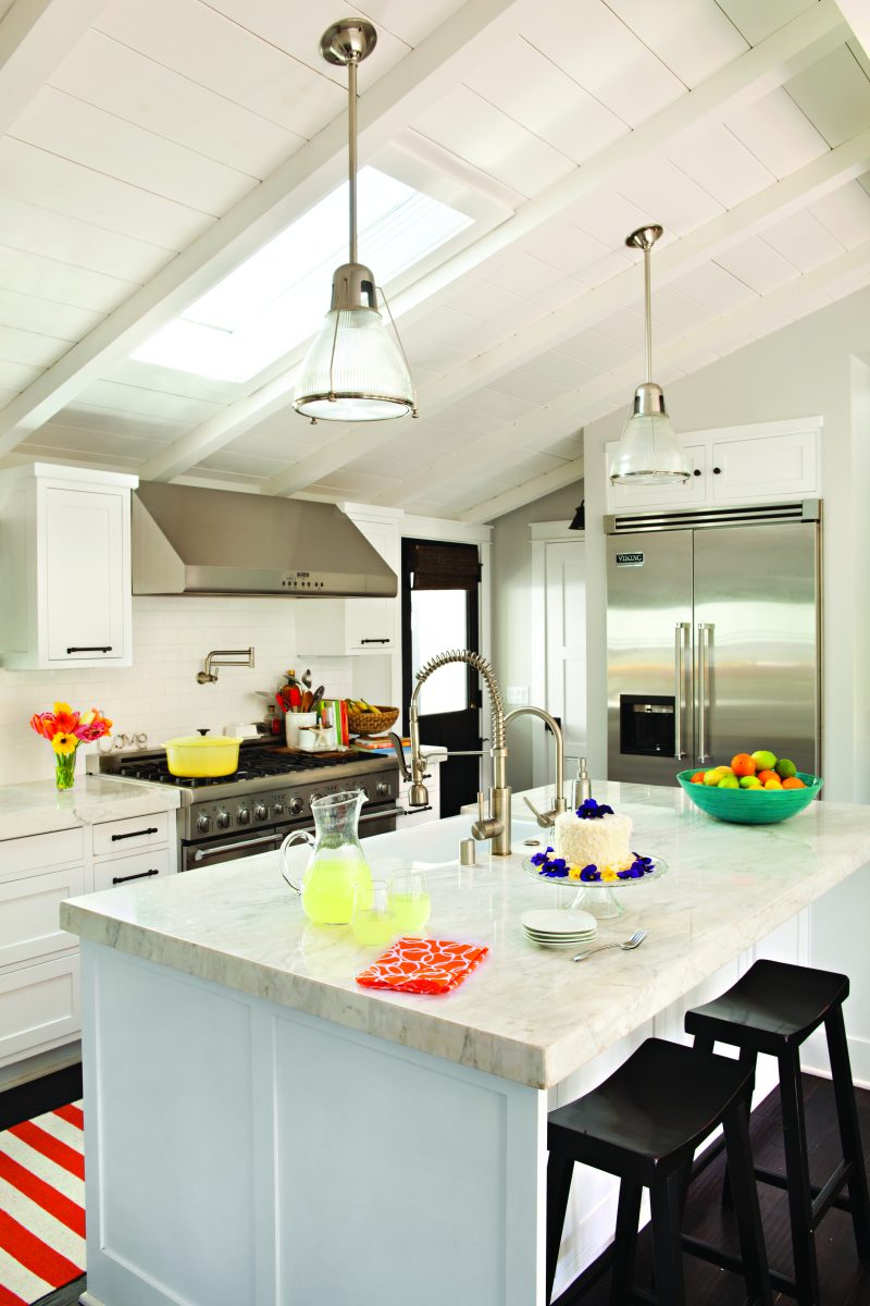 Cottage kitchen with white color palette, skylight and stainless steel appliances.