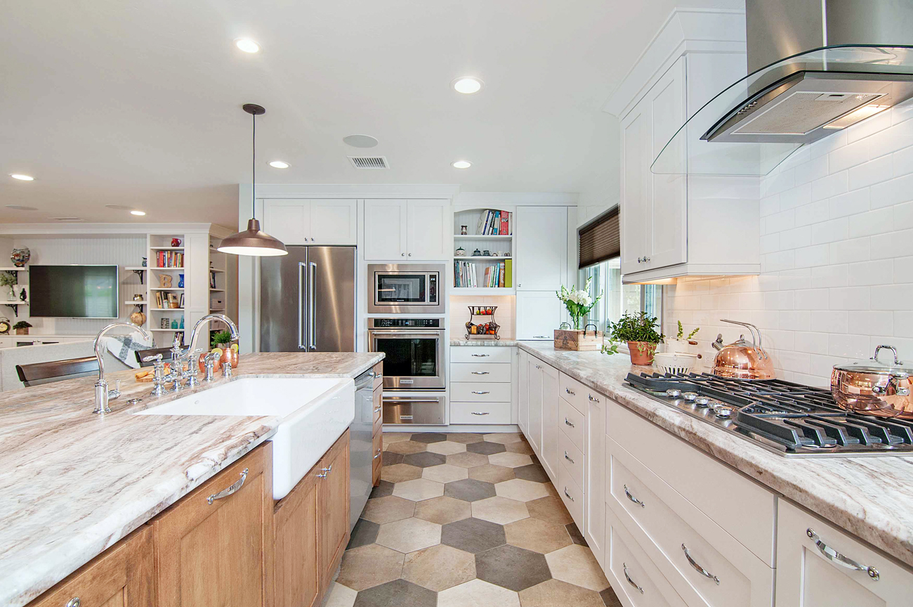 Open concept kitchen with white cabinets and hexagonal floor tiles.