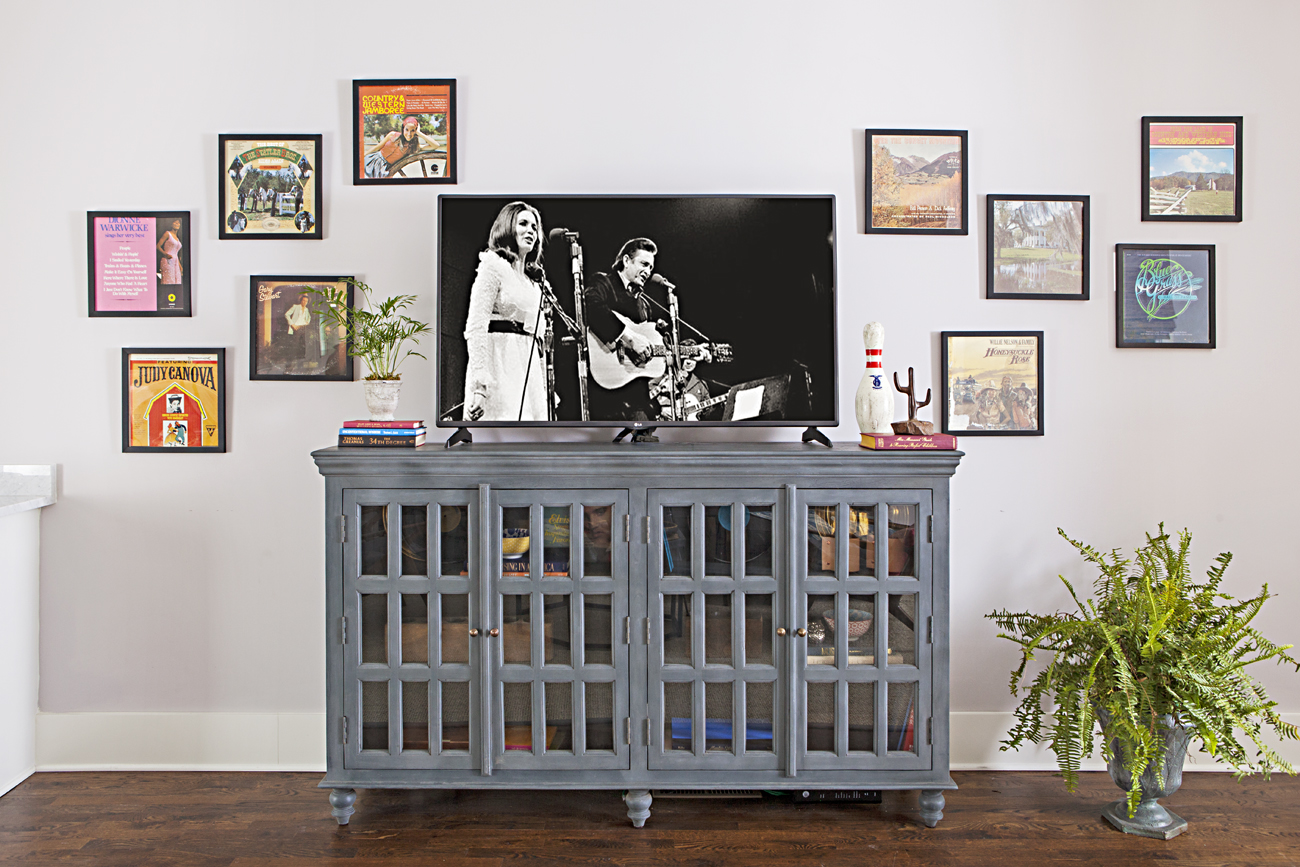 Gray painted media center with musical art prints hanging on the wall behind it. 