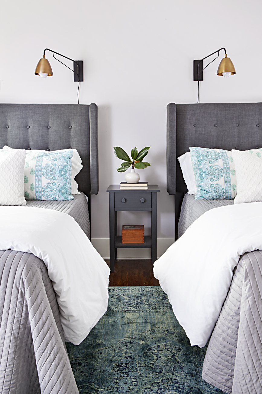 Guest bedroom with gray tufted headboard twin beds and vintage inspired blue rug. 