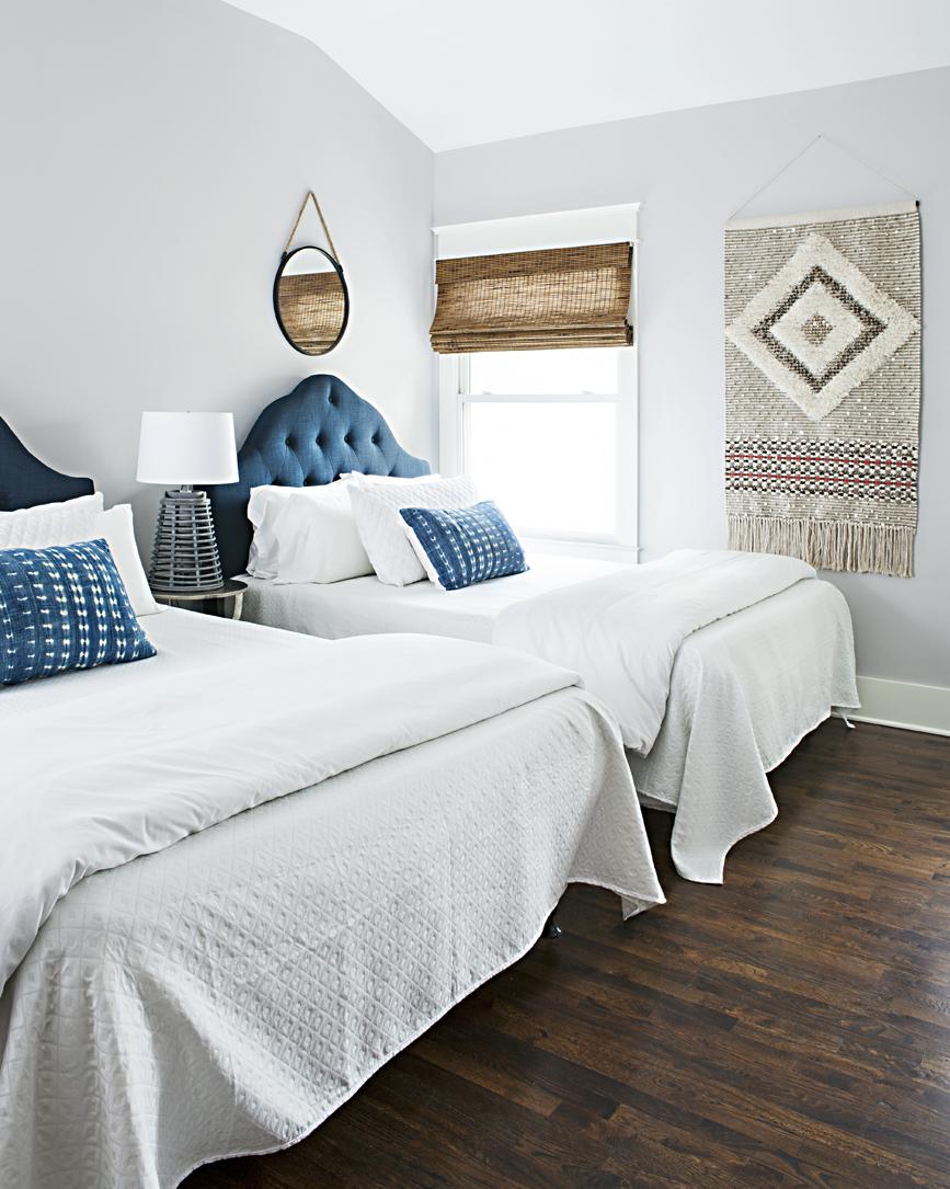 Bright and open room with twi queen sized beds with tinted velvet blue headboards and hanging wall art. 