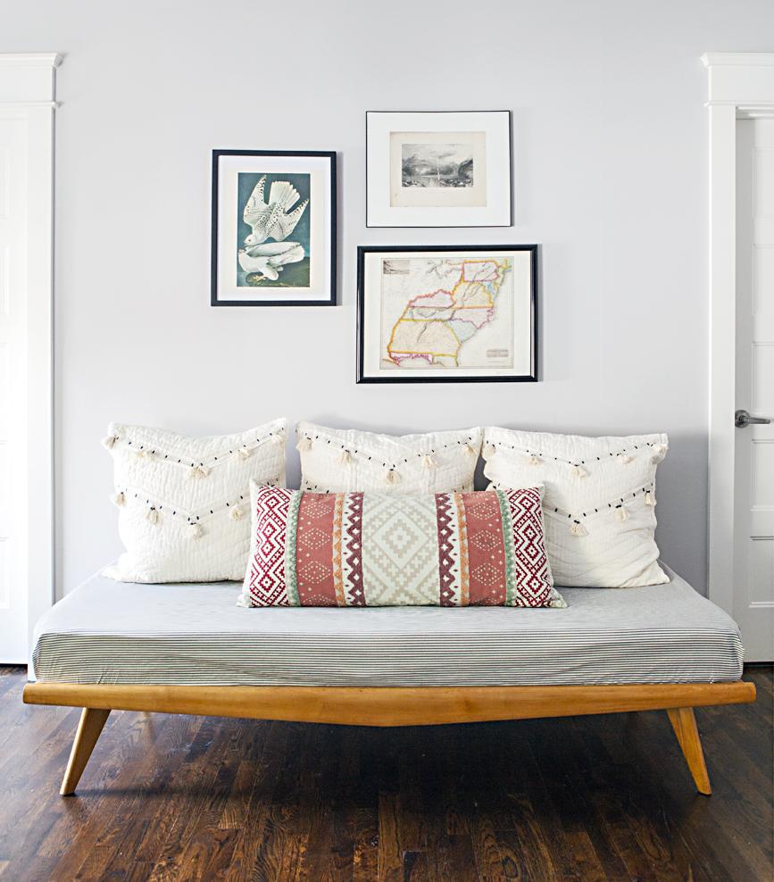 Hallway seating area with a modern design bench and art pieces hung on the light grey background wall. 