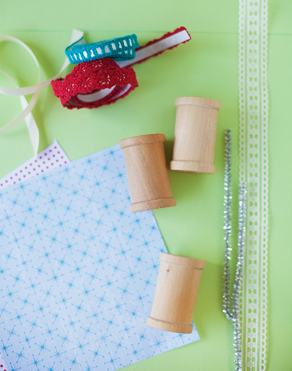 scrap paper. wooden craft spools and ribbon trim are ingredients for a DIY spool ornament