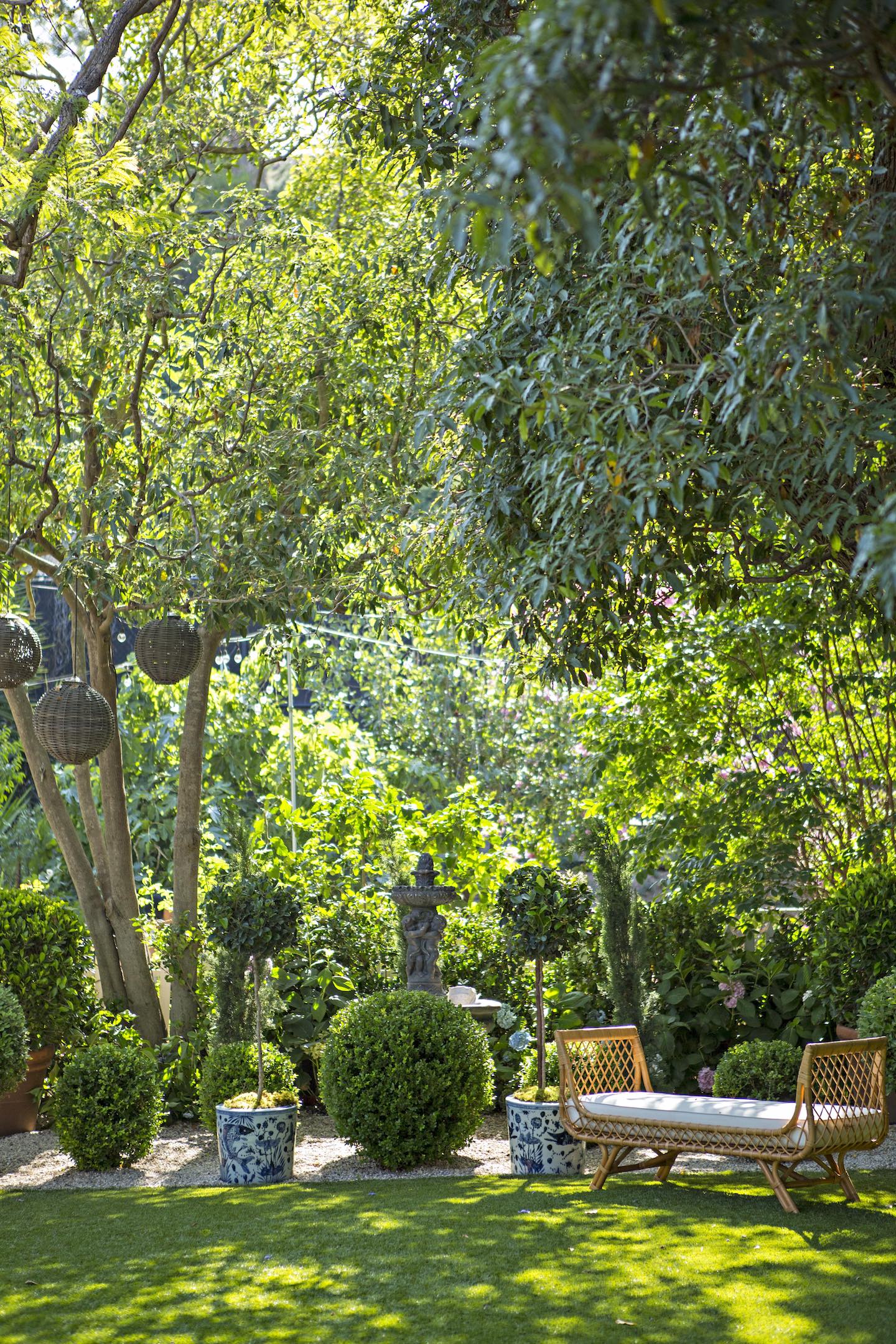 lush green garden with topiaries lanterns and a garden bench