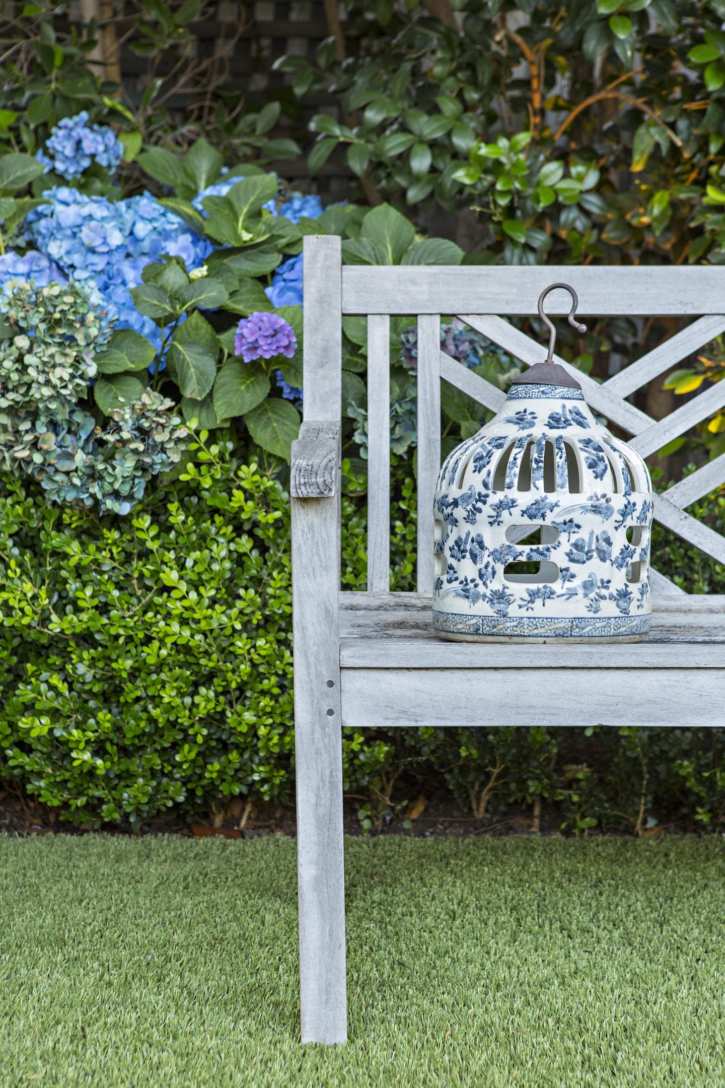 wooden garden bench with blue and white ceramic lantern