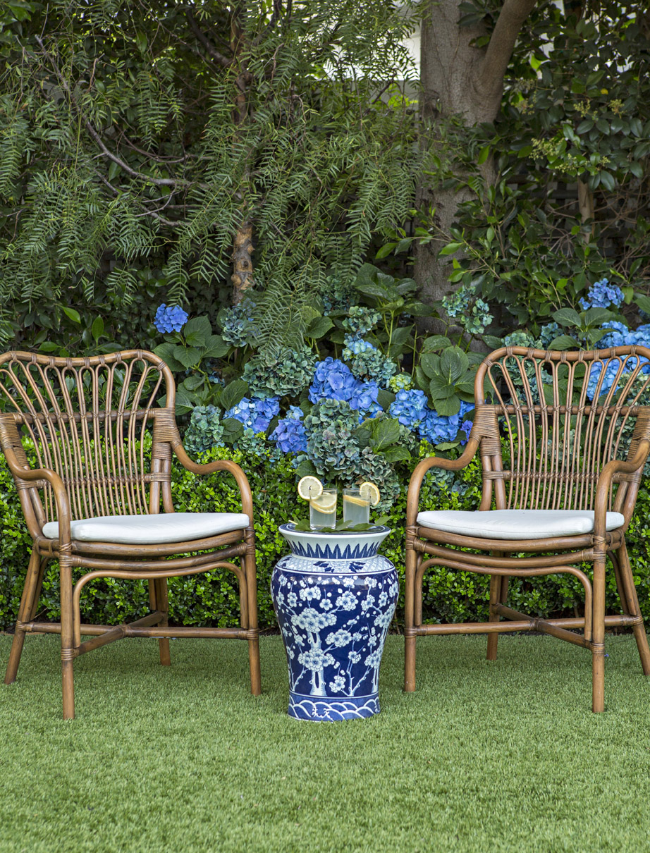 rattan chairs and a blue and white garden stool in front of hydragneas