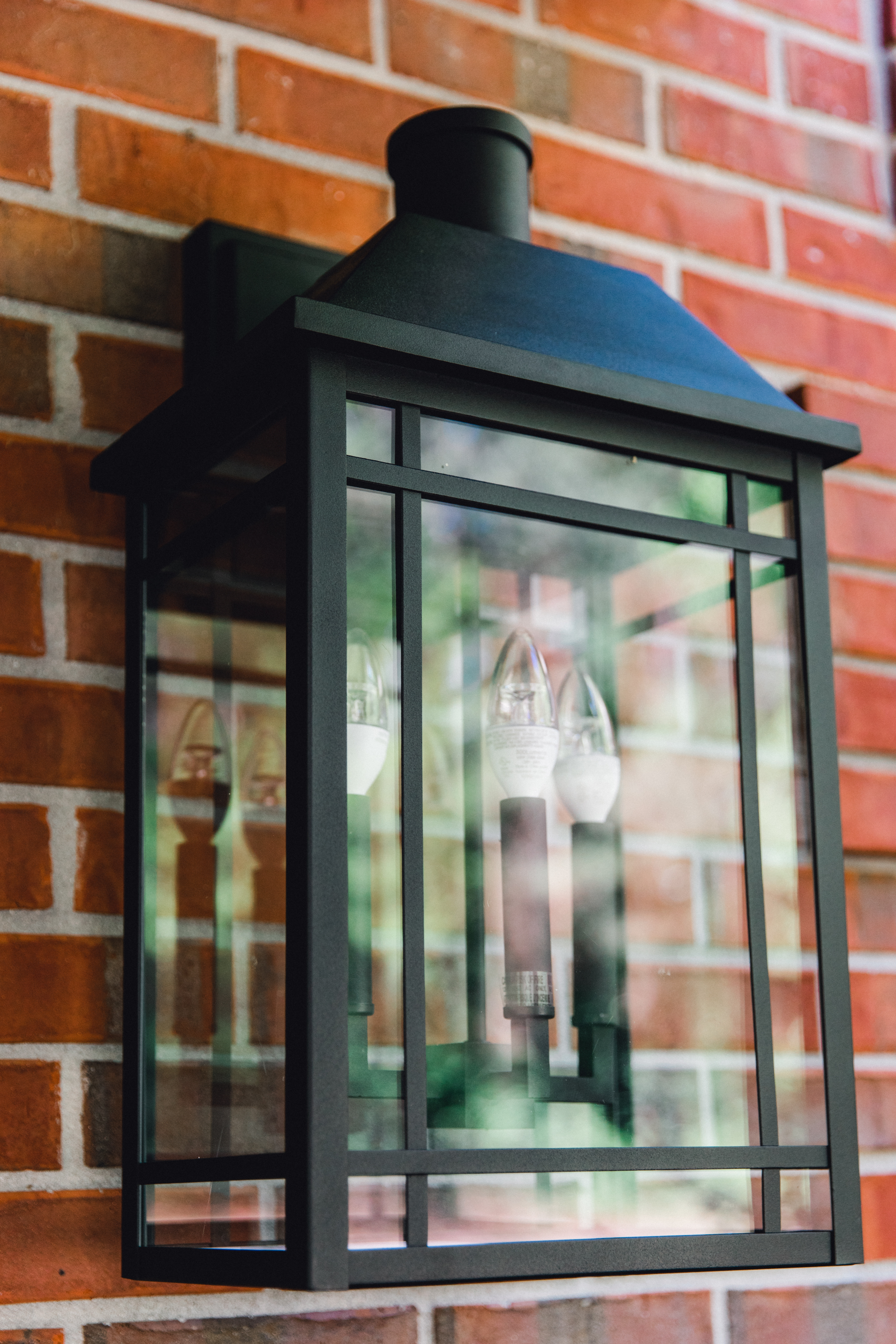 Close up of the Braden Lankford Outdoor Lantern from Capital Lighting black metal fixture mounted on brick