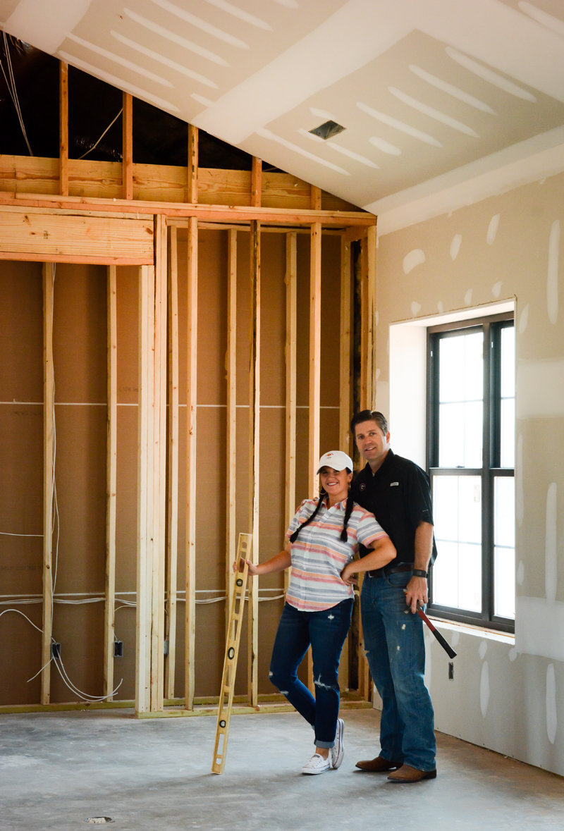 Katie and Ryan standing in the basic frame of their fixer upper farmhouse