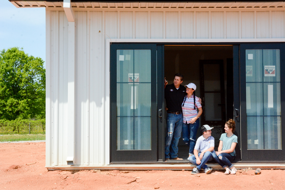 The Busentiz Family in front of their steel-framed farmhouse