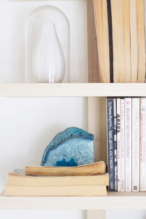 Books acting as décor is a functional and budget-friendly way to accent your home. A spectacular blue rock adds immediate earthiness to the shelf.