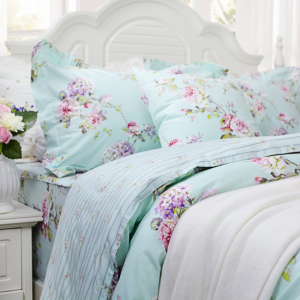 Light blue duvet bedding set with hydrangea flowers and a white wooden headboard.