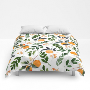 Comforter with orange grove designs on a white background.
