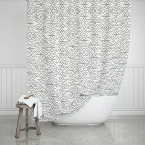 White shower curtain with a geometric design, draped over a white tub next to a small stool.