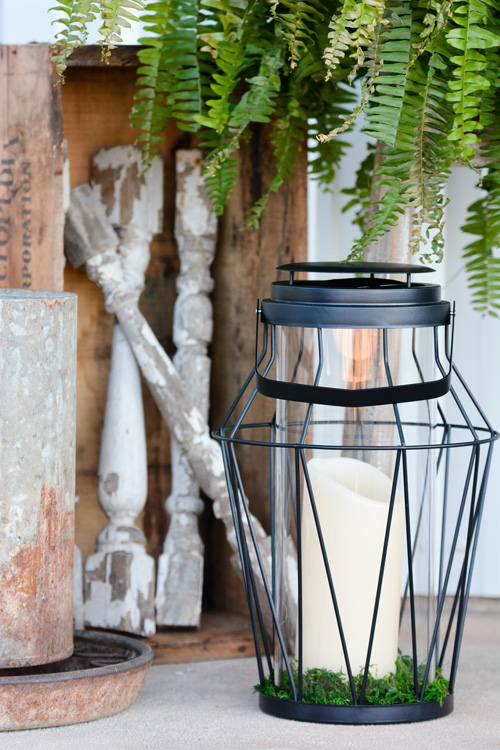 A mix of vibrant greens and vintage textures gives the porch a fresh, collected feel. The lantern sports a battery-powered candle with a timer—both from Balsam Hill—making it easy and fuss-free to entertain on the porch.