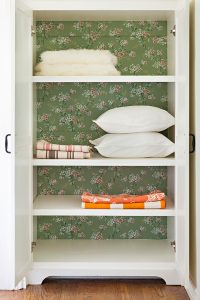 linen closet with vintage wallpaper added to the back