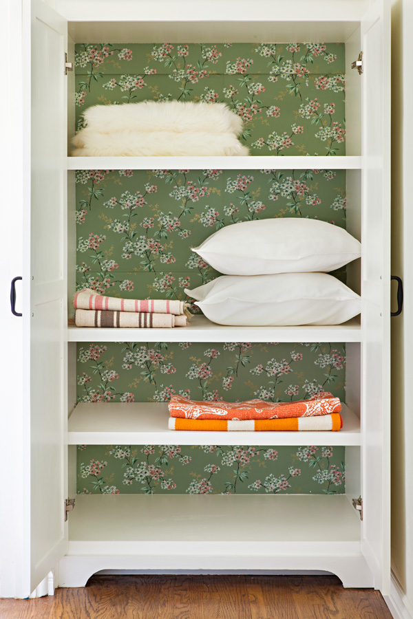 linen closet with vintage green floral wallpaper added to the back