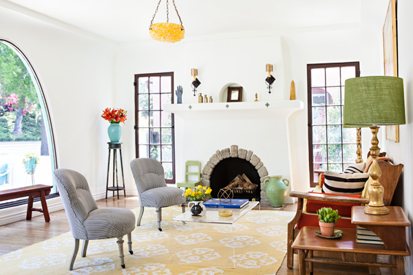 spanish bungalow living room with bright pops of color and a rounded fireplace opening. 