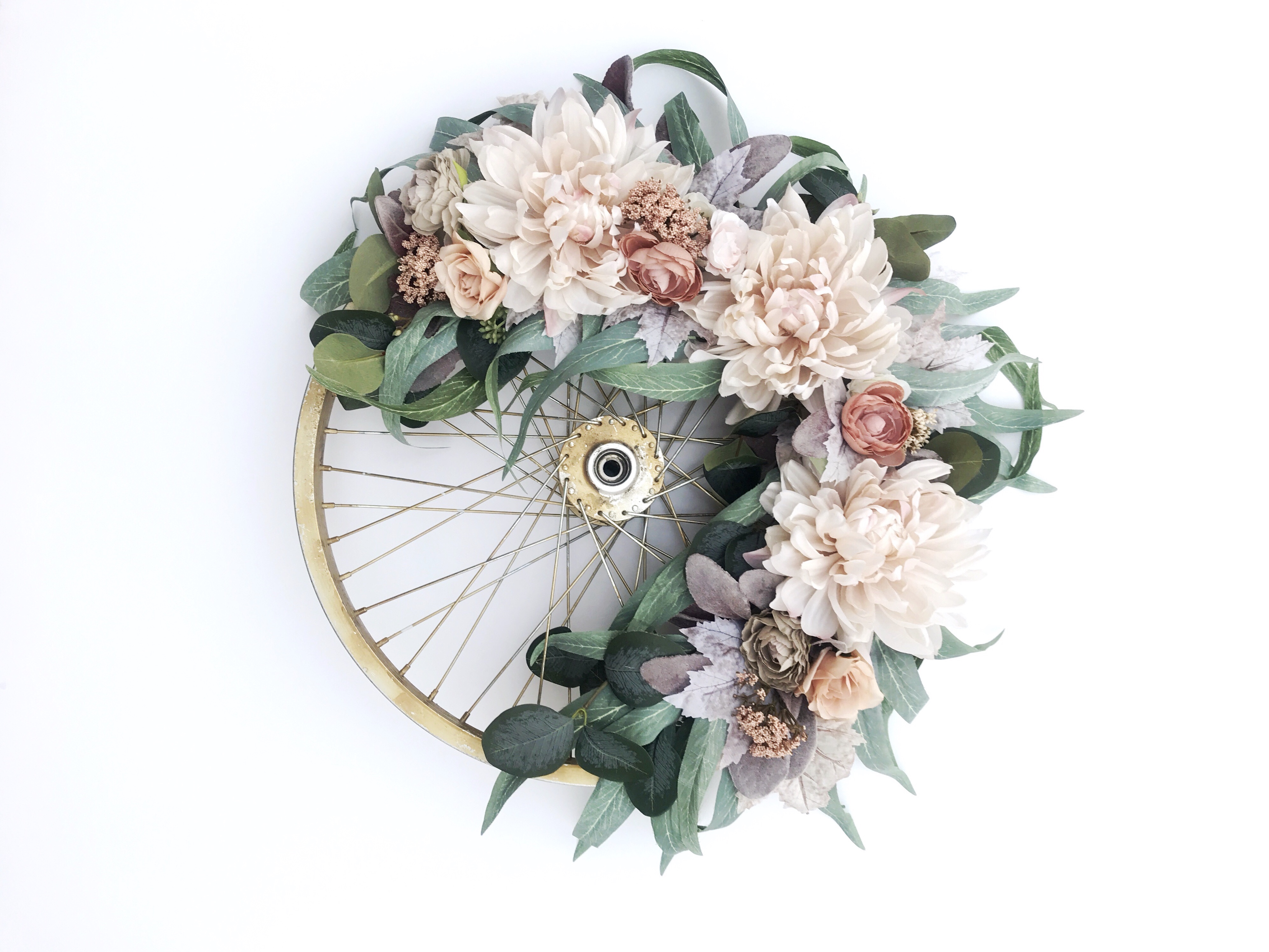 Round floral decorative bicycle wheel wreath with light pink flowers and greenery from Bloom Valley Market.
