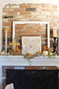 mantel with patinaed decorations, greenery and small white pumpkins