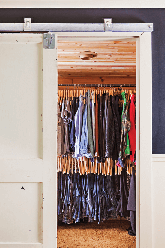 For a unique alternative to a standard sliding closet door, Melanie used an old barn door and hung it on a track. Inside the cedar-lined closet, metal pipe clothes rods give a rustic industrial sens