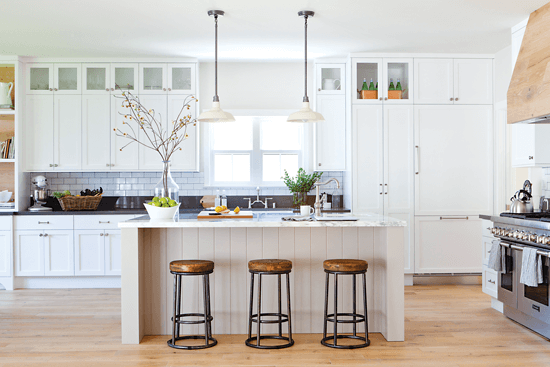 The distressed-oak range hood is a unique and rustic statement piece in this contemporary kitchen. Shabby yet chic barstools add rustic charm to the kitchen island.