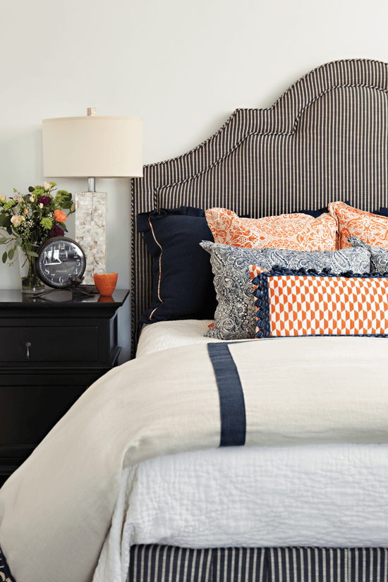 In one of the guest bedrooms, a black-and-white pinstriped headboard lends a graphic touch to the bright pillows.