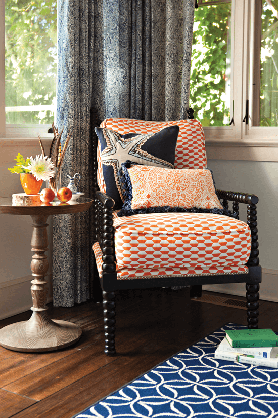 Seating area with orange-patterned armchair and decorative pillows.
