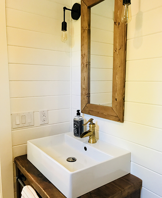 Bathroom vanity with wood-framed mirror and teardrop light fixtures.