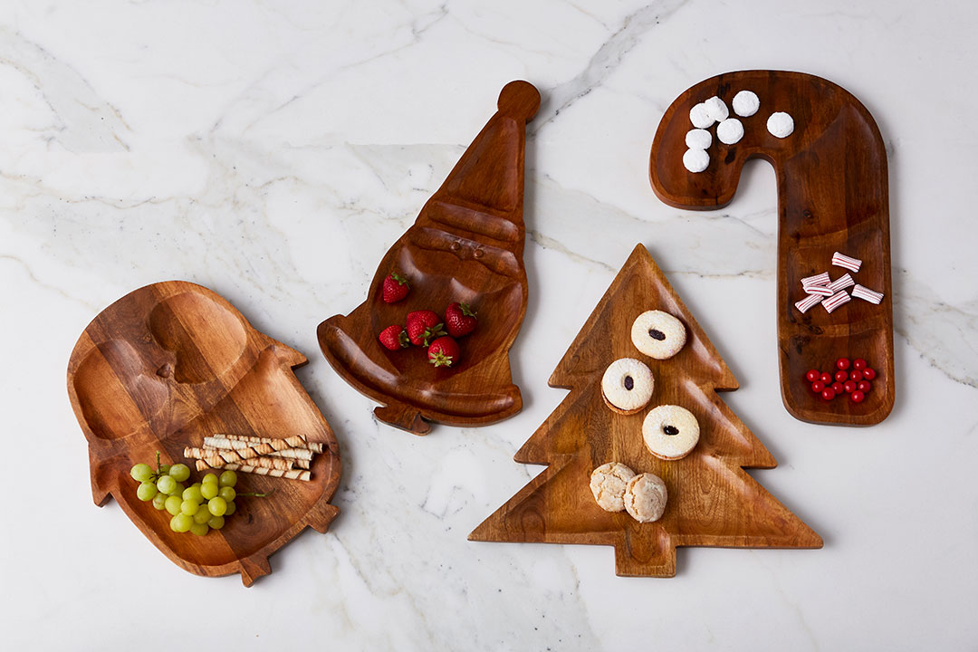 Carved mango wood platters featuring a penguin, Santa, a Christmas tree and a candy cane. 