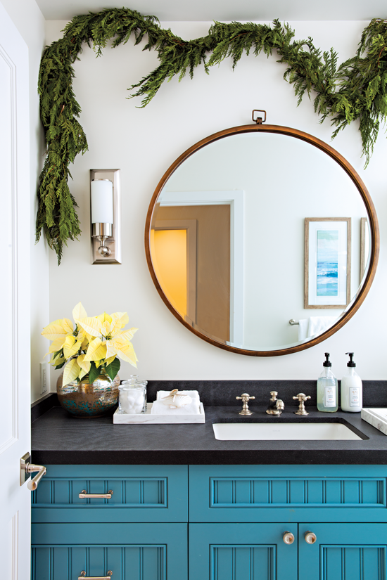 The space behind this coastal blue bathroom vanity is full of Christmas cheer with the addition of green garland.