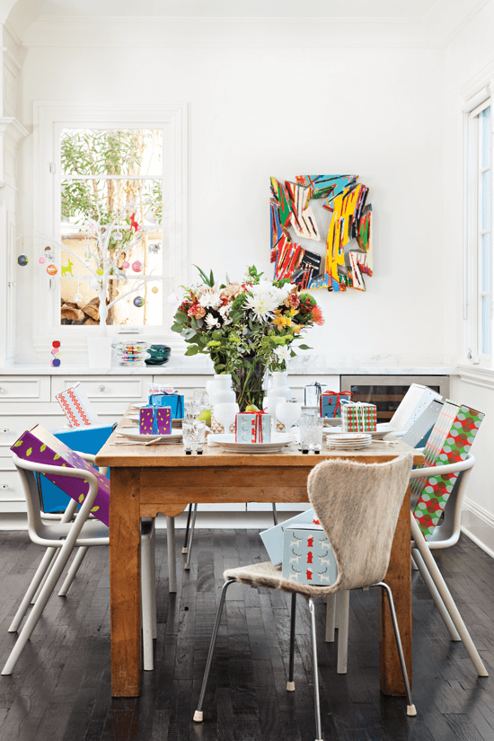 The old worn pine farm table stands in contrast to the all white kitchen and simple cabinets, adding a rustic feel. Modern dining chairs add to the mix.