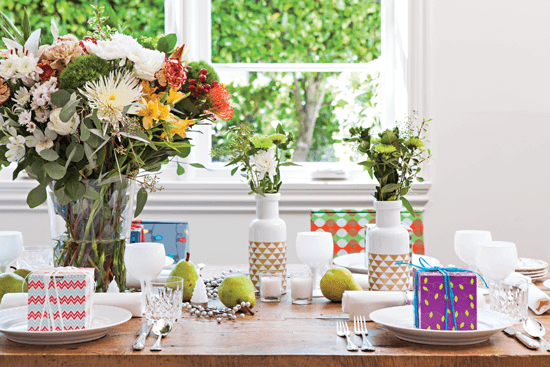 The table is adorned with a mix of modern milk-glass inspired vases, sparkling wintry accents and a large, lush natural flower arrangement.