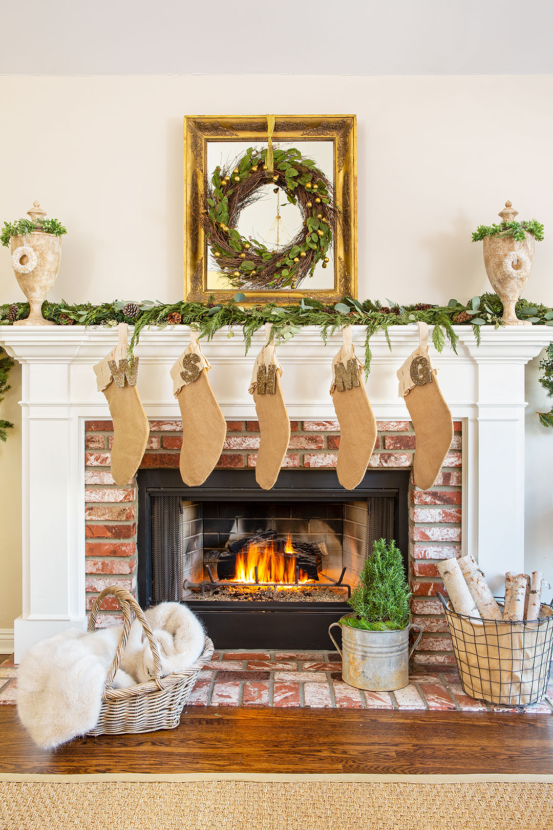 A living room mantel and fireplace with neutral decor and natural greenery