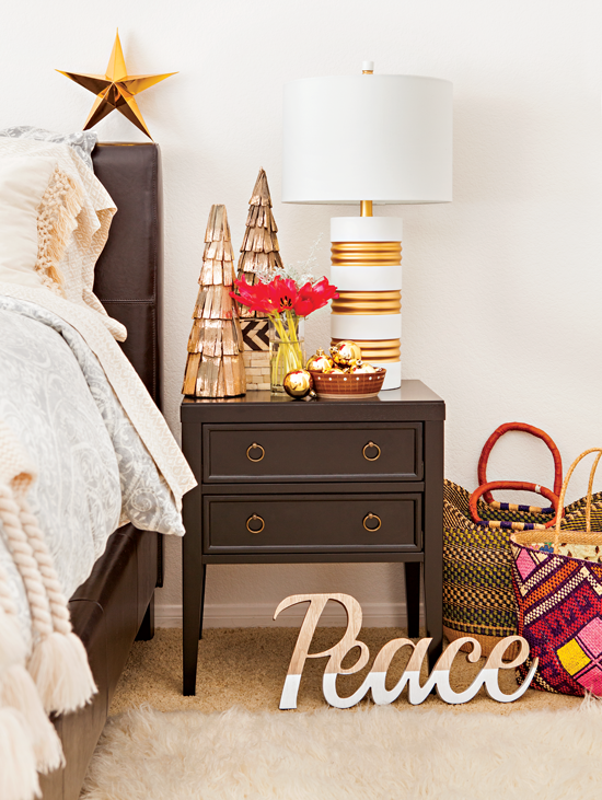 Bedroom size table decorated with simple Christmas tree figures, red flowers and gold ornaments.