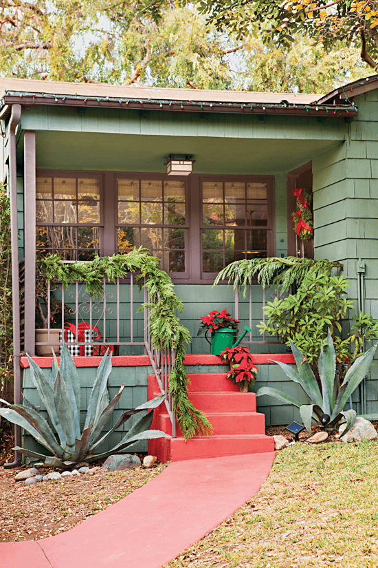 Front porch of home with a dark green exterior and red accents on the stairs and trim.