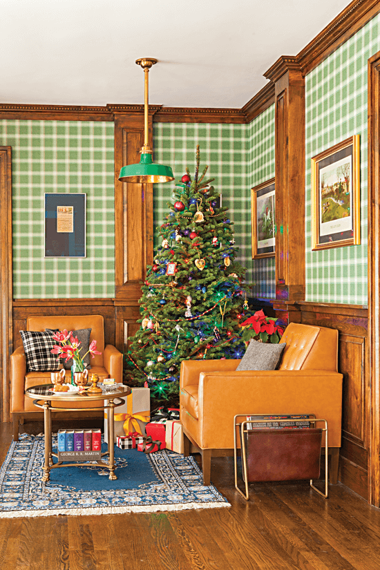 Cozy lounge area with adorned with British pub-inspired hues and a Christmas tree in the corner. Two tan armchairs are positioned on either side of the Christmas tree.