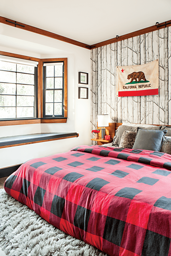 A cozy red-and-black plaid blanket is a seasonal addition to the bed, while the birch tree wallpaper and soft gray rug evokes snow.