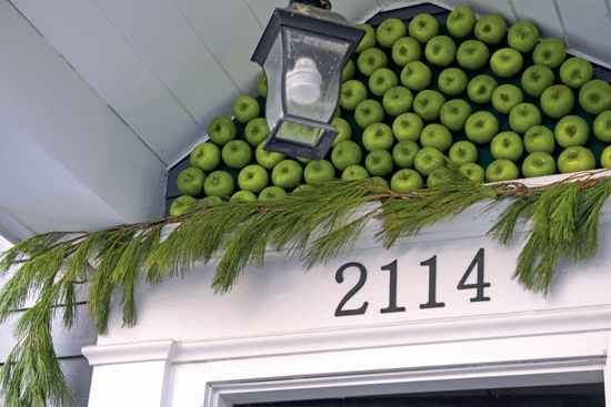 The space above the front door is decorated with textured greenery and green apples.