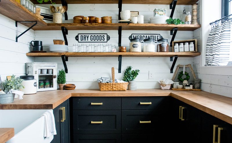 Farmhouse pantry with open shelves, black cabinetry and butcher block counters.