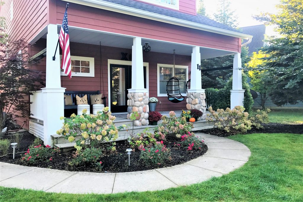 Front of the Victory Farms house with a meandering sidewalk and beautiful flowers.