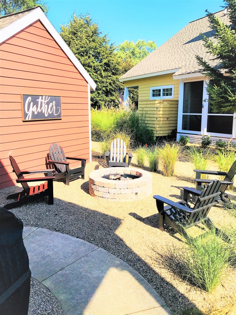 Brick fire pit with adirondack chairs in the backyard of the Victory Farms project.