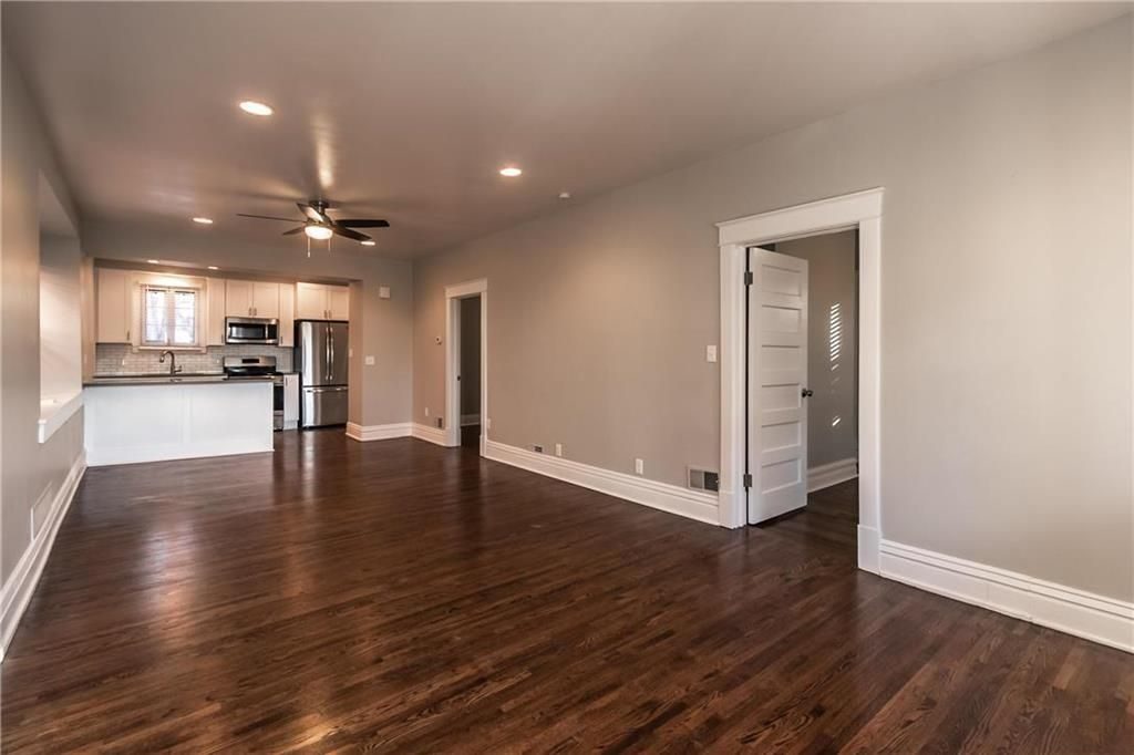 Large living space and kitchen of a Kansas City cottage, featuring dark wood floors and beautiful molding.