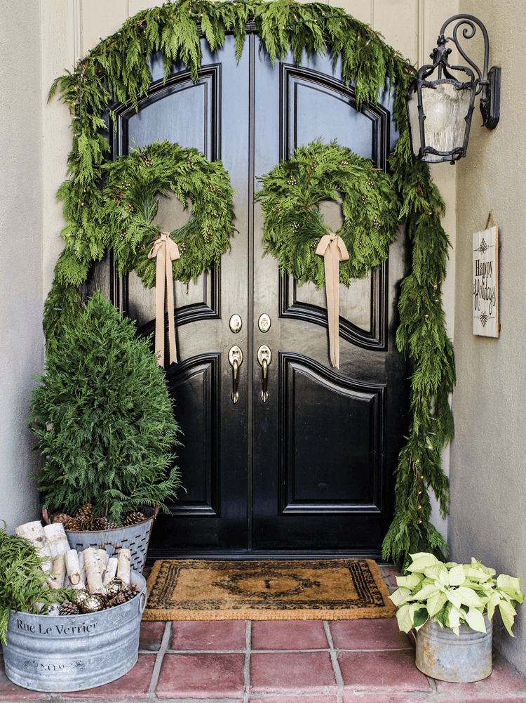 Fresh, natural greenery is the perfect front door decor with two wreaths and a garland over the door. 