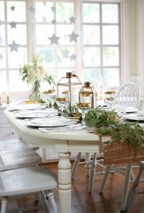New Year's Eve decor tablescape with lanterns, greens and a white table