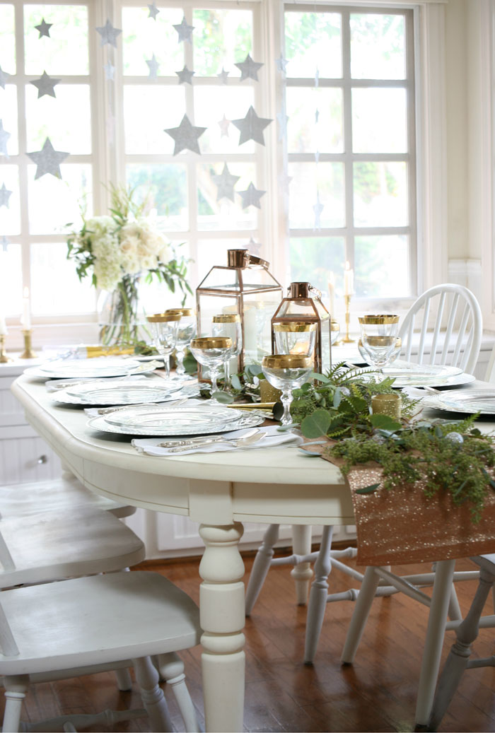 New Year's Eve table decor with lanterns, greens and a white table